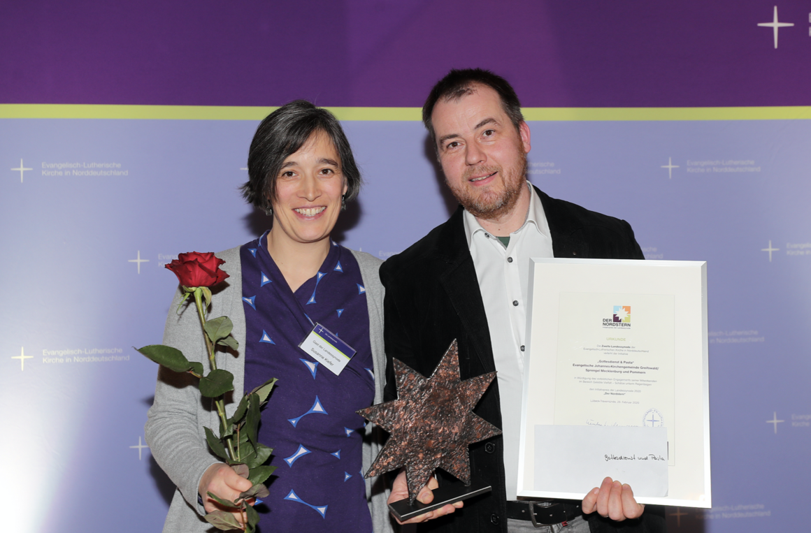 Eine Frau, ein Mann, mit Rose und Urkunde. "Gottesdienst und Pasta Greifswald" - Preisträger des Nordstern 2020